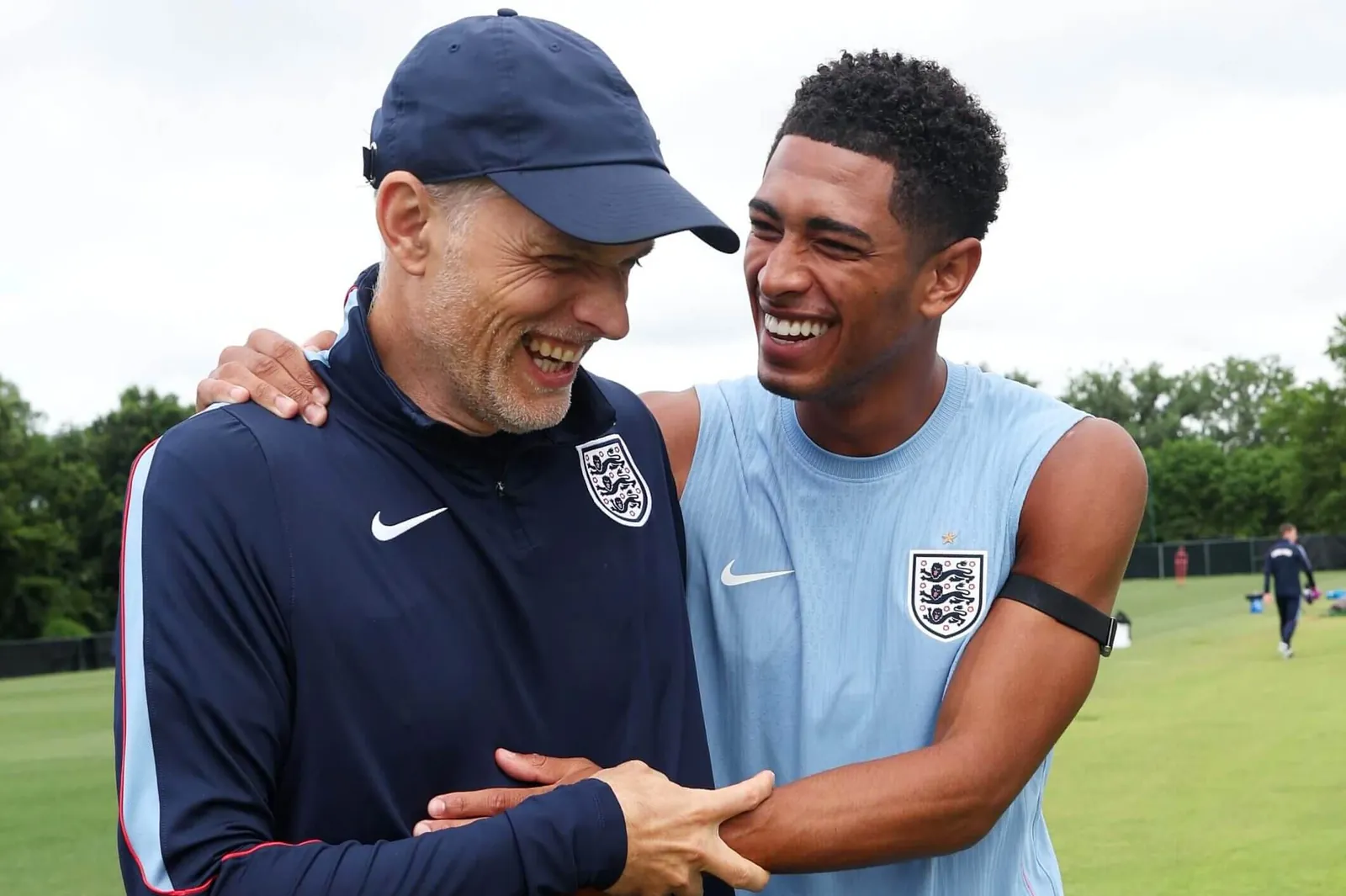 Thomas Tuchel and Jude Bellingham grasp each other as they share a joke during an England training session