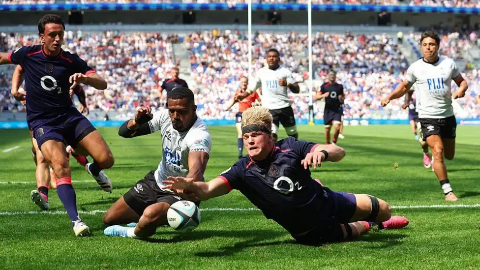 Henry Pollock is about to score his first try, beating Jiuta Wainiqolo to the ball to touch down as players from each side watch the pivotal moment
